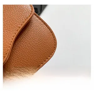 Close-up of brown litchi pattern leather texture and precise stitching on the handbag
