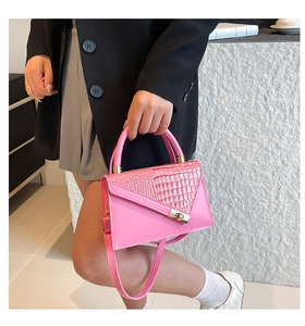 Detail of bright pink handbag with crocodile texture, gold clasp and top handle