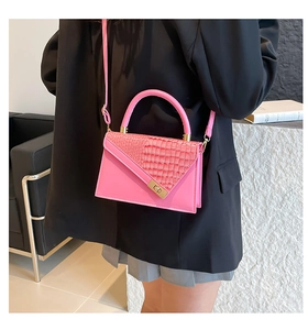 Detail of pink shoulder bag with croc-embossed texture and golden metal twist lock clasp