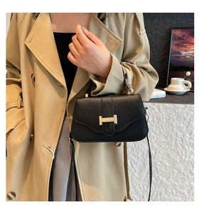 Detail of classic black lychee leather crossbody bag with iconic gold metal H-clasp