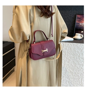 Burgundy textured leather crossbody bag styled with a khaki trench coat and gold hardware