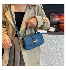 Detailed view of dark blue leather square bag with golden H-clasp and adjustable strap