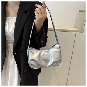 Dettaglio della borsa baguette argento metallizzato con trama a pieghe e tracolla alla moda