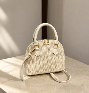 Detalle del bolso de paja trenzada beige con cremalleras doradas y textura