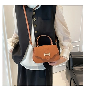 Detail of caramel leather crossbody bag featuring gold H-buckle and elegant handle strap