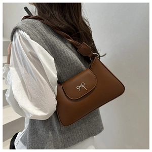 Sac sous le bras en cuir marron avec nœud argenté et sangle tressée sur modèle