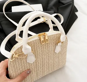 Detalle de bolso de paja beige con asas de cuero PU blanco y cremalleras doradas
