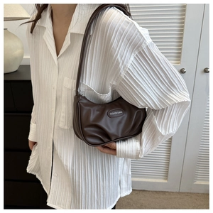 Dettaglio borsa a mezzaluna plissettata color caffè con toppa in pelle su camicia