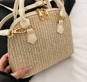 Detalle del bolso de paja con asa de cuero blanco y cremallera metálica dorada