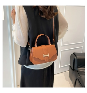 Caramel lychee leather square bag with gold metal clasp shown on model's shoulder