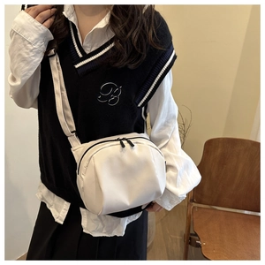 Minimalist white nylon shoulder bag with dual zippers worn by a model in casual setting