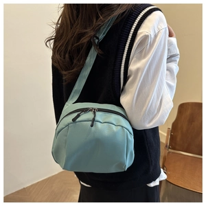 Light blue nylon crossbody bag with pleated detail shown on model in a casual style