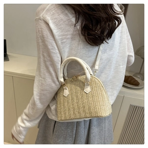 Detalle del bolso de concha trenzado beige con asa blanca y cremalleras doradas