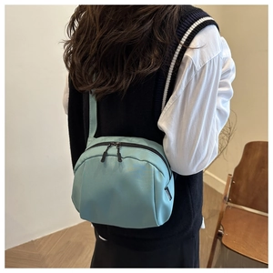 Detail of light green casual shell crossbody bag showing dual zippers and side label
