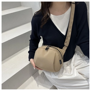 Detail of beige nylon crossbody bag with double zippers and adjustable shoulder strap