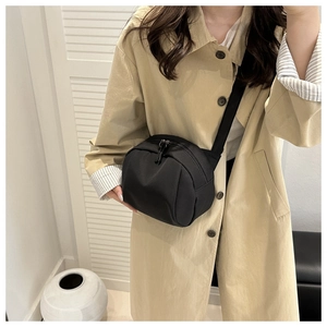 Minimalist black shell crossbody bag worn with a stylish beige trench coat for daily commute
