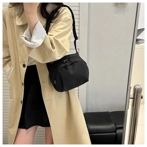 Close-up of black nylon crossbody bag featuring double zippers and adjustable strap