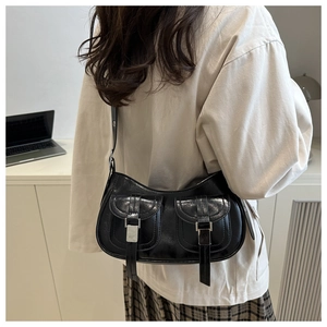 Detail of black glossy shoulder bag featuring double front pockets and silver metal buckles