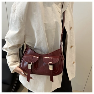 Detail of burgundy glossy leather shoulder bag with double flap pockets and silver buckles
