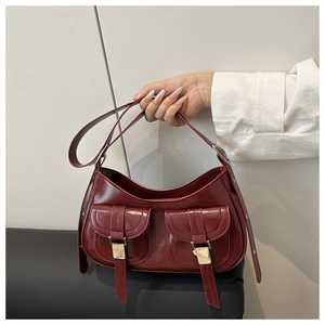 Detail of burgundy glossy leather hobo bag with signature utility pockets and silver buckles