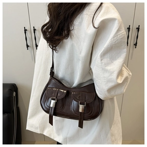 Detail of dark brown faux leather shoulder bag with silver buckles and retro pockets