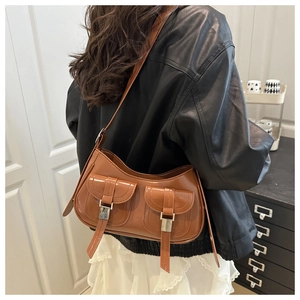 Close-up of caramel leather shoulder bag with double buckled pockets and retro design