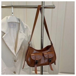 Close-up of brown PU leather shoulder bag featuring dual pockets with silver metal buckles