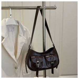 Detail of dark brown glossy shoulder bag featuring silver buckle pockets and adjustable strap