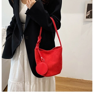 Dettaglio della borsa a secchiello in camoscio rosso con tracolla a nodo e mini charm