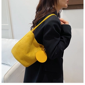 Borsa a secchiello in camoscio giallo con mini pochette tonda indossata da modella