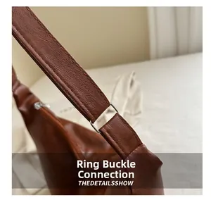 Detail aus Leder mit Litschi-Muster und silberner D-Ring Schnalle an brauner Tasche