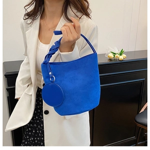 Dettaglio della borsa a secchiello in pelle scamosciata blu con manico intrecciato e charm
