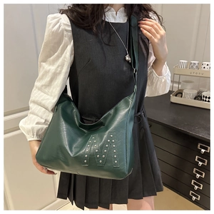 Detailed view of deep green leather tote bag with silver stud M design on shoulder