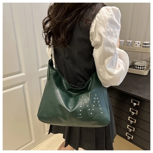 Deep green leather hobo bag with stud M detail shown on shoulder for size context