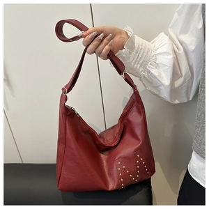 Detail of burgundy PU leather tote bag featuring silver rivet M pattern and wide strap
