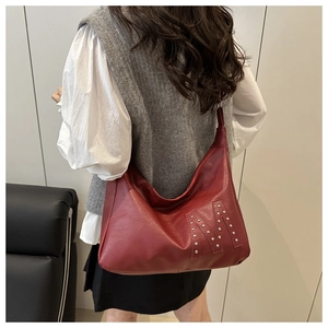 Close-up of silver studs forming the letter M on a red leather large tote shoulder bag