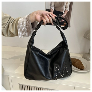 Detail of matte black leather tote featuring silver stud M-shaped pattern and wide strap