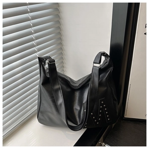 Detail of silver rivets forming an M shape on a black faux leather large tote bag
