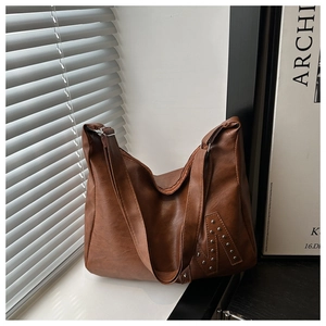 Detailed macro view of silver studs forming letter N on brown pebbled leather tote bag