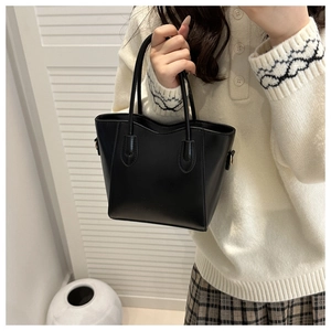Close-up of black leather mini bucket bag with metallic hooks and embossed logo detail
