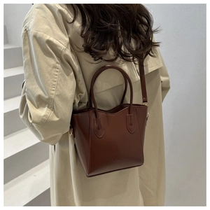 Detail of dark brown leather tote with dual handles and embossed fashion text