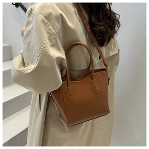 Brown leather bucket bag detail with FASHION lettering and adjustable shoulder strap