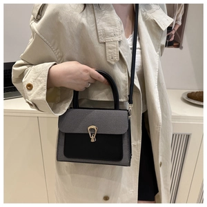 Detail of grey fabric and black leather texture on stylish crossbody bag with gold lock