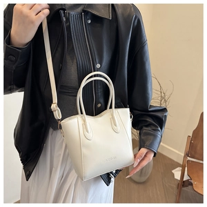 Detailansicht einer weißen Mode-Eimertasche aus Leder mit Doppelgriffen und Schultergurt