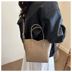 Detail of light beige tote bag with embossed fashion text and adjustable shoulder strap