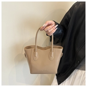 Detail of light brown leather handbag featuring embossed FASHION text and metal buckle