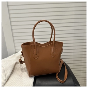 Detail of a brown leather tote bag with FASHION engraving and detachable shoulder strap