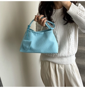 Detail of light blue woven texture and knotted handle on this trendy baguette bag