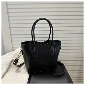 Detail of black trapezoid bucket bag with rounded handles and fashion embossed text