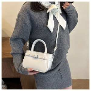 Détail d'un mini sac seau blanc avec boucle métallique et fine bandoulière réglable